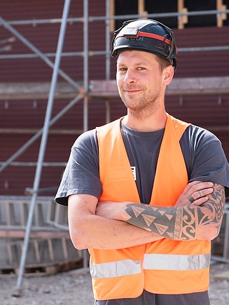 Photo of a young man with tattoos on his arm. Internship ZÜBLIN Timber.