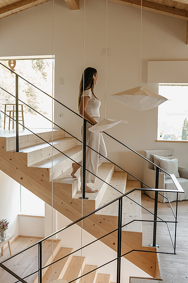 Photo of a hotel room. In the middle is a staircase down which a woman is walking.