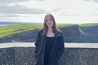 Foto einer jungen Frau in Irland an der Küste.
