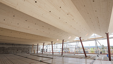 Photo of a building site. You can see a folding roof structure with LENO cross-laminated timber elements