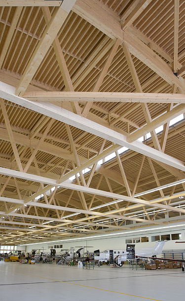 Foto der Montagehalle Pilatus CH-Stans. Zu sehen ist eine große Brettschichtholz-Dachkonstruktion.