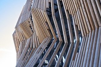 Fassadenbau bei ZÜBLIN Timber. Projekt APASSIONATA Park München GmbH & Co. KG Foto eines Detailausschnittes einer Holzfassade mit einzelnen Holzlamellen.
