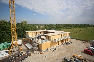 Baustellenfoto, auf dem die Montage der ersten Brettsperrholzelemente zu sehen ist.