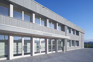 Foto der Sporthalle des Gymnasiums in Diedorf. Holzbau von außen.