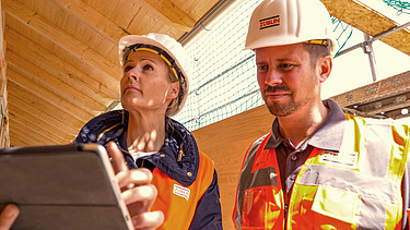 Foto von zwei Personen auf einer Holzbaubaustelle.