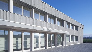 Foto der Sporthalle des Gymnasiums in Diedorf. Holzbau von außen.