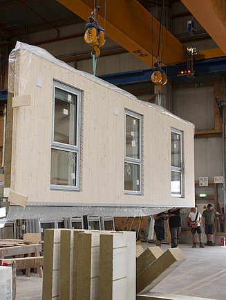 Foto einer LENO-ADD-Außenwand mit integrierten Fenstern in der Werkshalle von ZÜBLIN Timber.