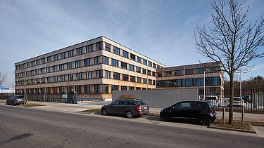 Photo of the Flexim Berlin office building from the outside. You can see a large wooden building with a wooden façade and flat roof.