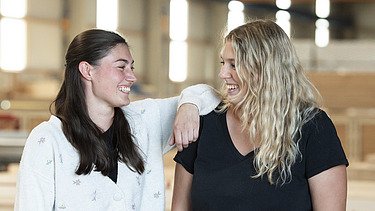Photo of two ZÜBLIN Timber employees smiling at each other.
