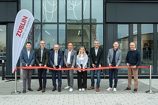 Aktuelles ZÜBLIN Timber Foto mit 8 Personen vor dem Büro T3, die ein rotes Band durchschneiden.