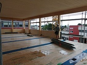 Foto eines Rohbaus aus Holz. Man sieht einen Innenraum der ersten Etage 