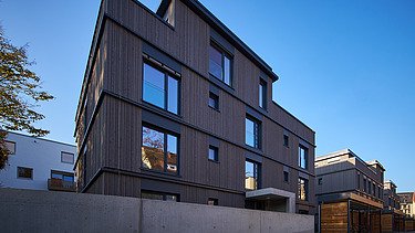 Foto eines mehrgeschossigen Wohngebäudes mit Holzfassade.