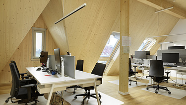 Photo of an interior shot of an office space. The sloping LENO cross-laminated timber walls and ceilings are clearly visible.