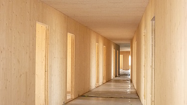 Foto eines Flures im Rohbau. Man sieht viele LENO-Brettsperrholz-Oberflächen.