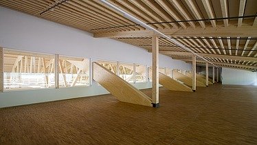 Photo of the Pilatus CH-Stans assembly hall. A glulam roof construction can be seen.