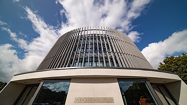 Foto des Globe Theaters in Coburg. Zu sehen ist der Eingangsbereich des runden Gebäudes aus Holz.