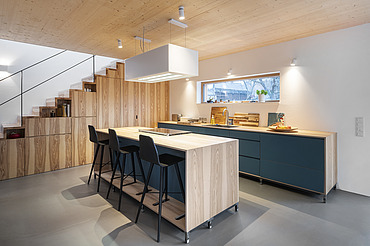 Foto eines Küchenwohnraumes mit sichtbarer LENO-Brettsperrholzdecke.