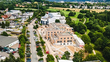 Photo of Witten University from the outside. You can see a large wooden building from a bird's eye view.