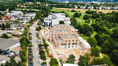 Photo of Witten University from the outside. You can see a large wooden building from a bird's eye view.