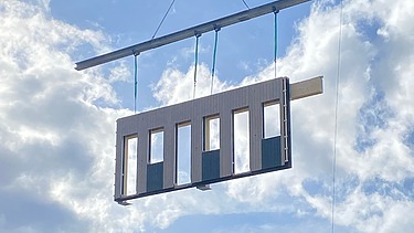 Foto eines schwebenden Holzrahmenbauelements am Kran. Baustelle Büro T3 von ZÜBLIN Timber.