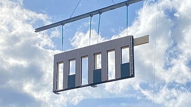 Photo of a floating timber frame construction element on the crane. Construction site office T3 from ZÜBLIN Timber.