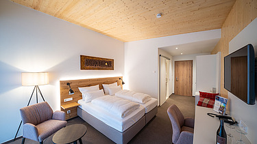Foto eines Hotelzimmers im Weinhotel Gengenbach. Zu sehen ist ein möblierter Raum und eine LENO-Holzdecke.