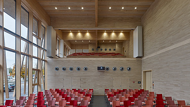 Photo of a room with red seating and many wooden surfaces. JOWAT House of Technology.