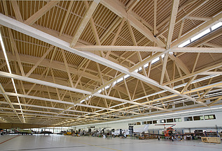Foto der Montagehalle Pilatus CH-Stans. Zu sehen ist eine große Brettschichtholz-Dachkonstruktion.