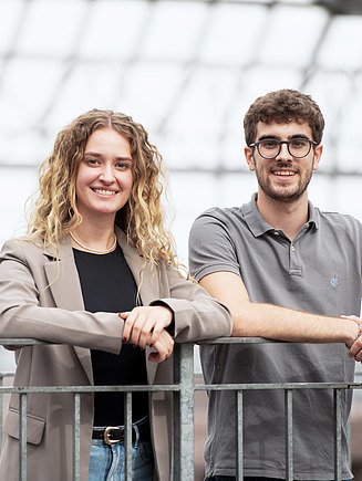 Photo of two young people standing at a railing. Students at ZÜBLIN Timber.