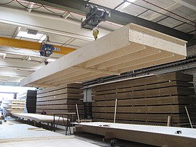Photo of a large rib element on the crane in the ZÜBLIN Timber production hall.