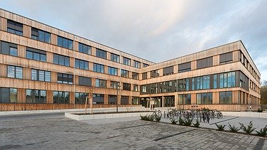 Photo of the Flexim Berlin office building from the outside. You can see a large wooden building with a wooden façade and flat roof.