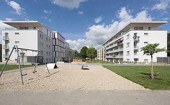 Photo of two multi-storey buildings with garden in front. Wooden extensions.