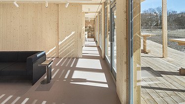 Photo of an interior with many wooden surfaces and a glass front.
