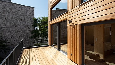 Foto eines Holzhauses. Detailbild der Holzterrasse im 1. Stock.