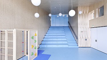 Foto des Flurbereichs des Kindergarten Ebersberg. Man sieht viele Holzoberflächen an Wänden und Decken.