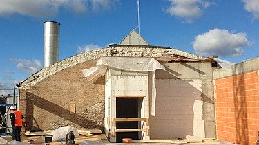 Photo of a building site. You can see the old stone core of the building on which wood is being added.