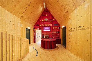 Foto des NEXT500-Pavillons auf dem Augsburger Marktplatz. Sie sehen eine moderne Inneneinrichtung aus Holz.