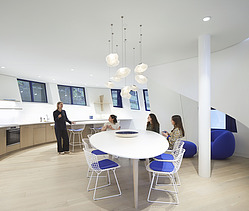 Photo of a recreation room. Four women are in the room. Three are sitting, one is standing.