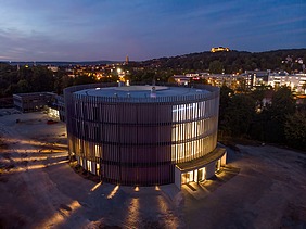 Nachtaufnahme des Globe Theaters in Coburg. Zu sehen ist ein rundes Gebäude aus Holz.