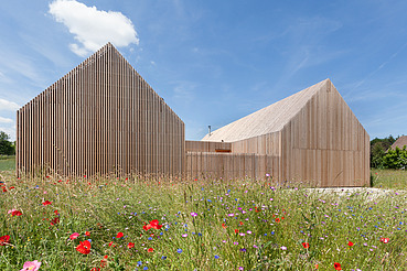 Foto eines modernen Holzhauses in U-Form mit Holzfassade. LENO-BSP.
