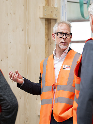 Three men talking in the ZÜBLIN Timber production hall.
