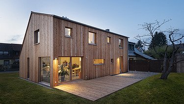 Photo of a modern wooden house. Dusk.