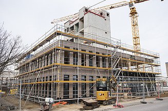 Foto des Rohbaus von Außen des Büroneubaus T3 in Aichach. Man sieht ein eingerüstetes Holzgebäude.