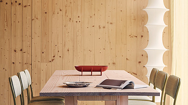 Photo of an interior of the Black and White office in London. You can see wooden surfaces and a table with chairs.