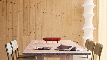 Photo of an interior of the Black and White office in London. You can see wooden surfaces and a table with chairs.