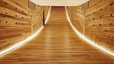 Foto eines beleuchteten, geschwungenen Innenraums aus Holz der Skulptur The Smile des Design Festivals in London.