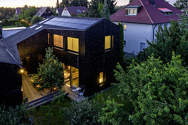 Photo of a wooden house with a dark wooden façade. Evening mood.