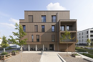 Foto von einem mehrgeschossigen Gebäude aus Holz und mit Holzfassade.
