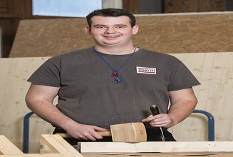 Photo of a young carpenter working on a small wooden element.