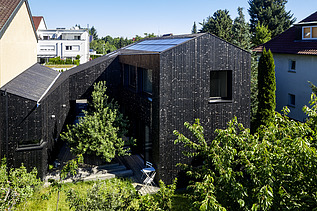 Foto eines Wohnhauses aus Holz und mit dunkler Holzfassade.